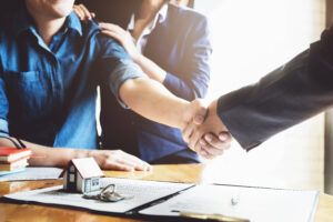 Picture of an attorney shaking hands with clients who are closing on a house.