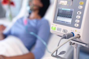 Picture of a woman in a hospital bed with a ventilator and a monitor.