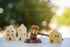 Picture of three miniature house figurines and a gavel.