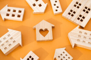 Picture of wooden figurines of houses, with a heart cutout in the center of one.