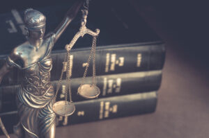 Picture of a scales of justice statue in front of a stack of three law books.