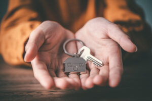 Picture of a person's hands holding a key on a house-shaped keychain.