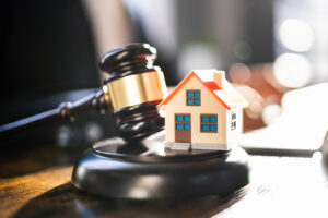 Picture of a gavel and a miniature house figurine.