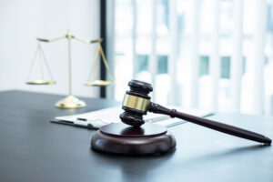 Picture of a gavel, a clipboard, and the scales of justice sitting next to each other on a table.