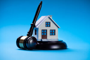 Picture of a gavel and a miniature house figurine.