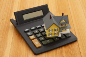 Picture of a house figurine sitting on top of a calculator.