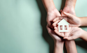 Picture of a family holding a wooden figure of a house in their hands.