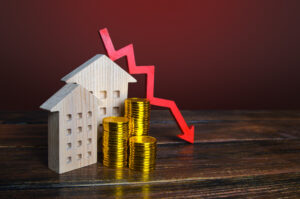 Picture of stacks of coins and wooden figures of houses and a red arrow.