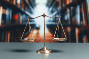 Picture of the scales of justice sitting on a table with bookshelves in the background.