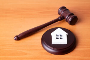 Picture of a white wooden house cutout on top of a gavel.