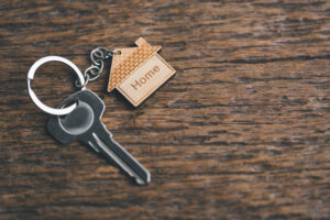 Picture of a key with a house-shaped keychain sitting on a wooden table.