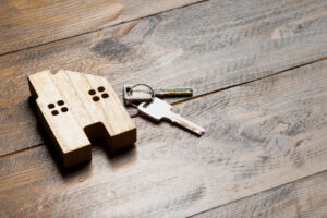 Picture of keys and a house-shaped keychain sitting on a wooden table.