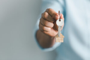 Picture of a woman holding a key with a house-shaped keychain.