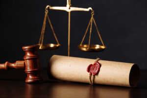 Picture of a gavel, the scales of justice, and a roll of parchment with a wax seal.