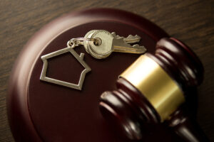 Picture of keys and a house-shaped keychain sitting on a gavel.