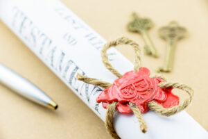 Picture of a pen, a scroll with a red wax seal, and two keys.