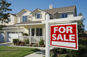 Picture of a For Sale sign in front of a house.