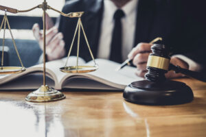 Picture of an estate planning attorney reviewing documents with the scales of justice and a gavel sitting on his desk.