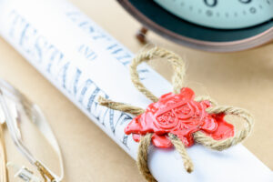 Picture of a pair of glasses, a will with a wax seal, and a clock.