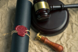 Picture of a scroll with a wax seal, a gavel, and a stamp.