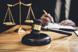 Picture of a probate lawyer sitting at a desk writing, with the scales of justice and a gavel in front of him.