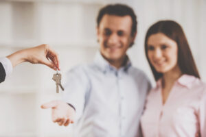 Picture of a realtor handing house keys to a man and a woman.